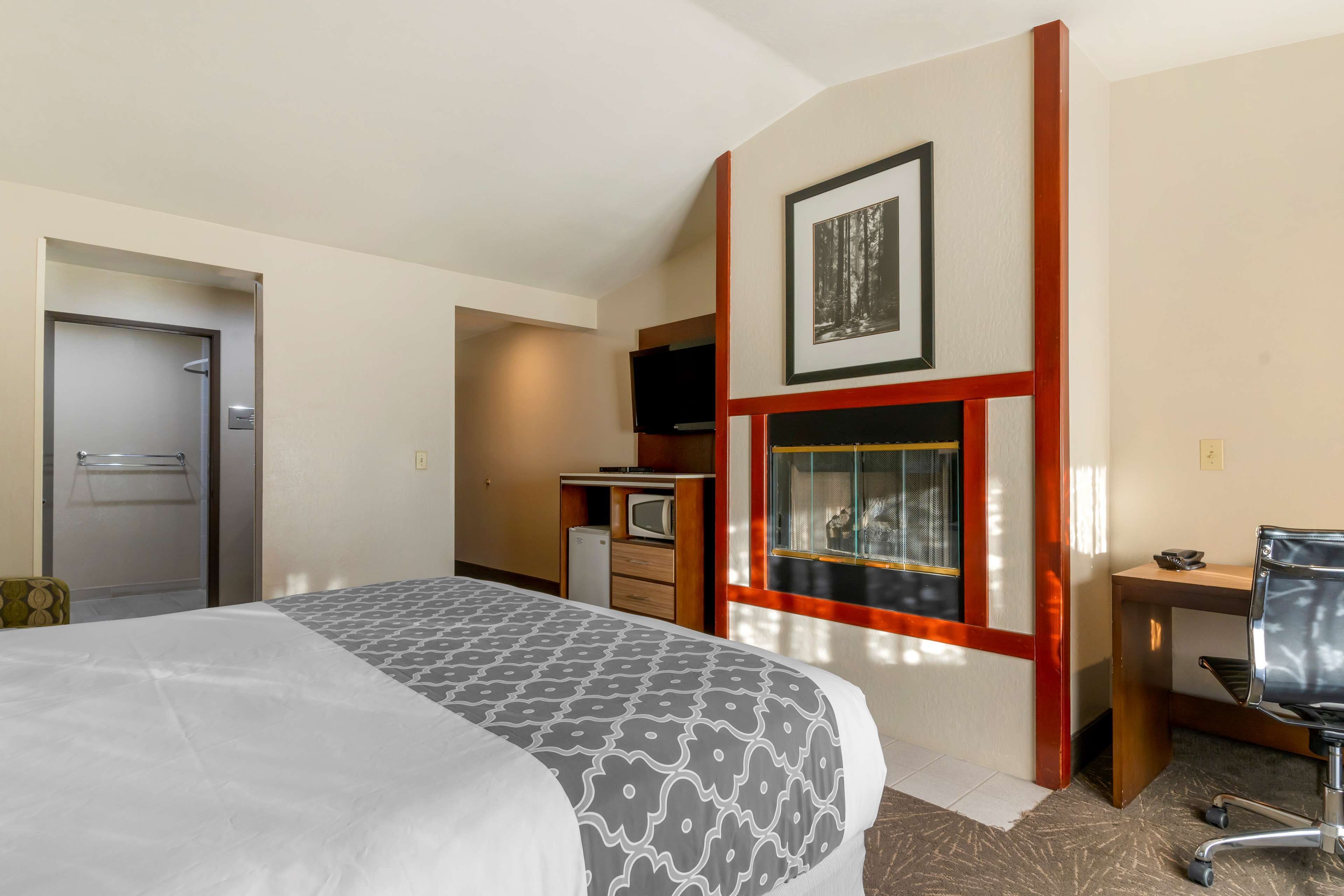A hotel room with a bed, a desk, a television, and a window with a view of the outside.