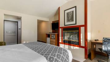 A hotel room with a bed, a desk, a television, and a window with a view of the outside.
