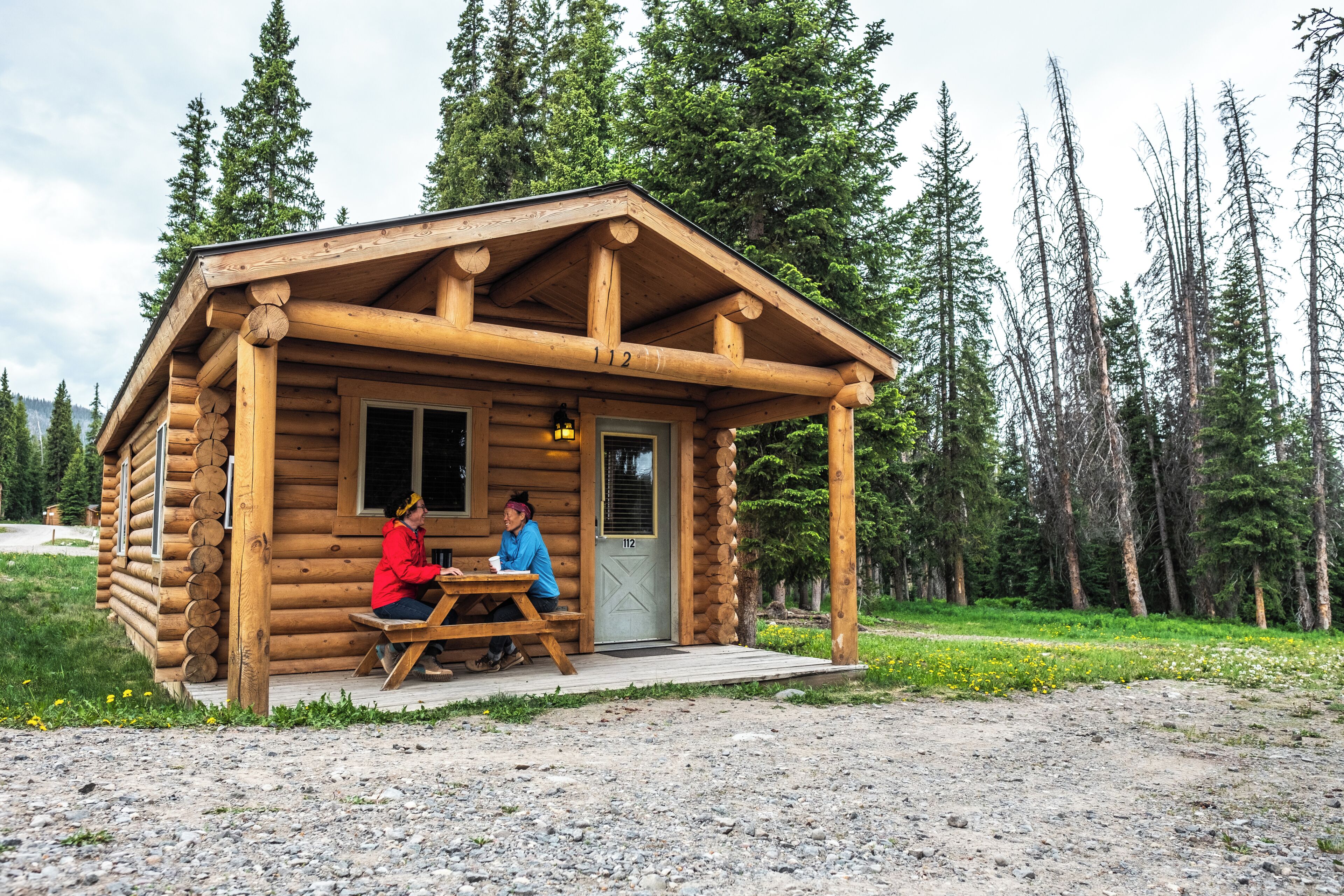 A wooden cabin with a porch, a door, and a window.