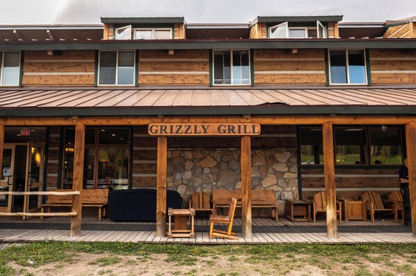 A wooden building with a sign reading 'Grizzly Grill' and outdoor seating. - Togwotee Mountain Lodge (Moran)