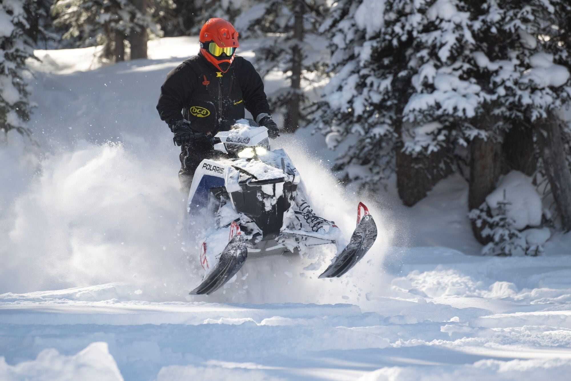 A person riding a snowmobile on a snowy path.