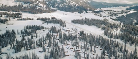 Un paisaje montañoso cubierto de nieve con varias cabañas y una estación de esquí.
