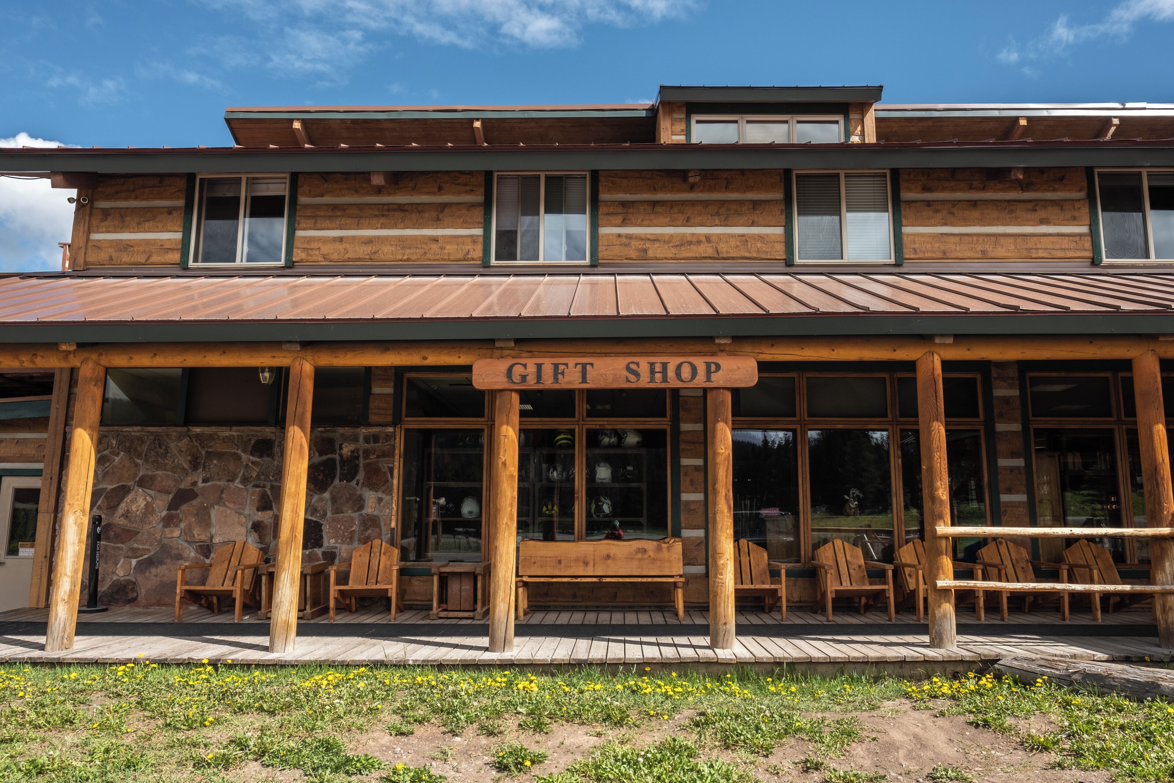 A wooden building with a 'GIFT SHOP' sign, stone walls, wooden benches, and a covered patio area.