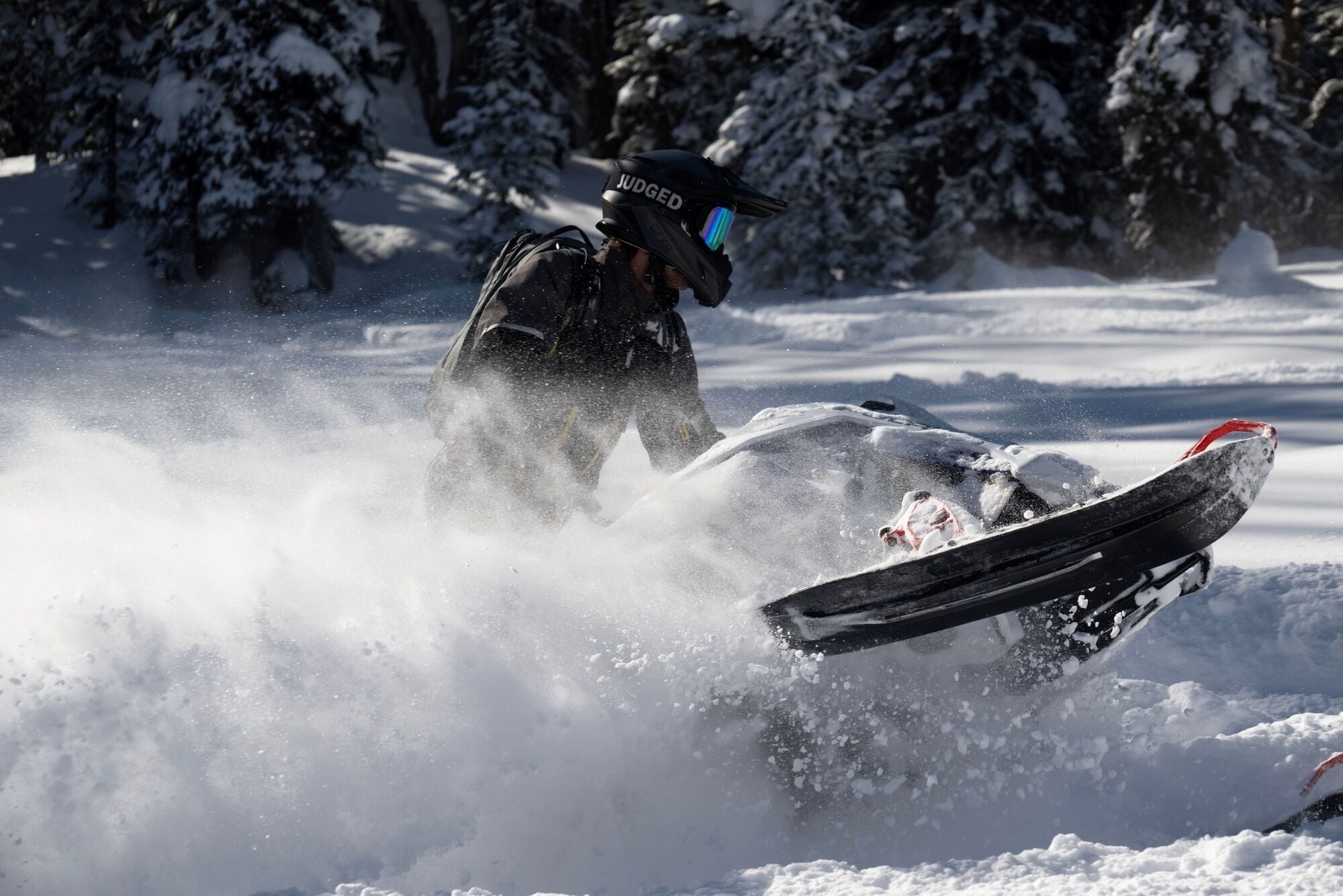 A person riding a snowmobile in a snowy landscape.
