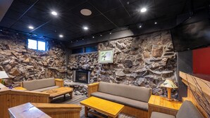 A cozy interior with a stone wall, a fireplace, and wooden furniture.