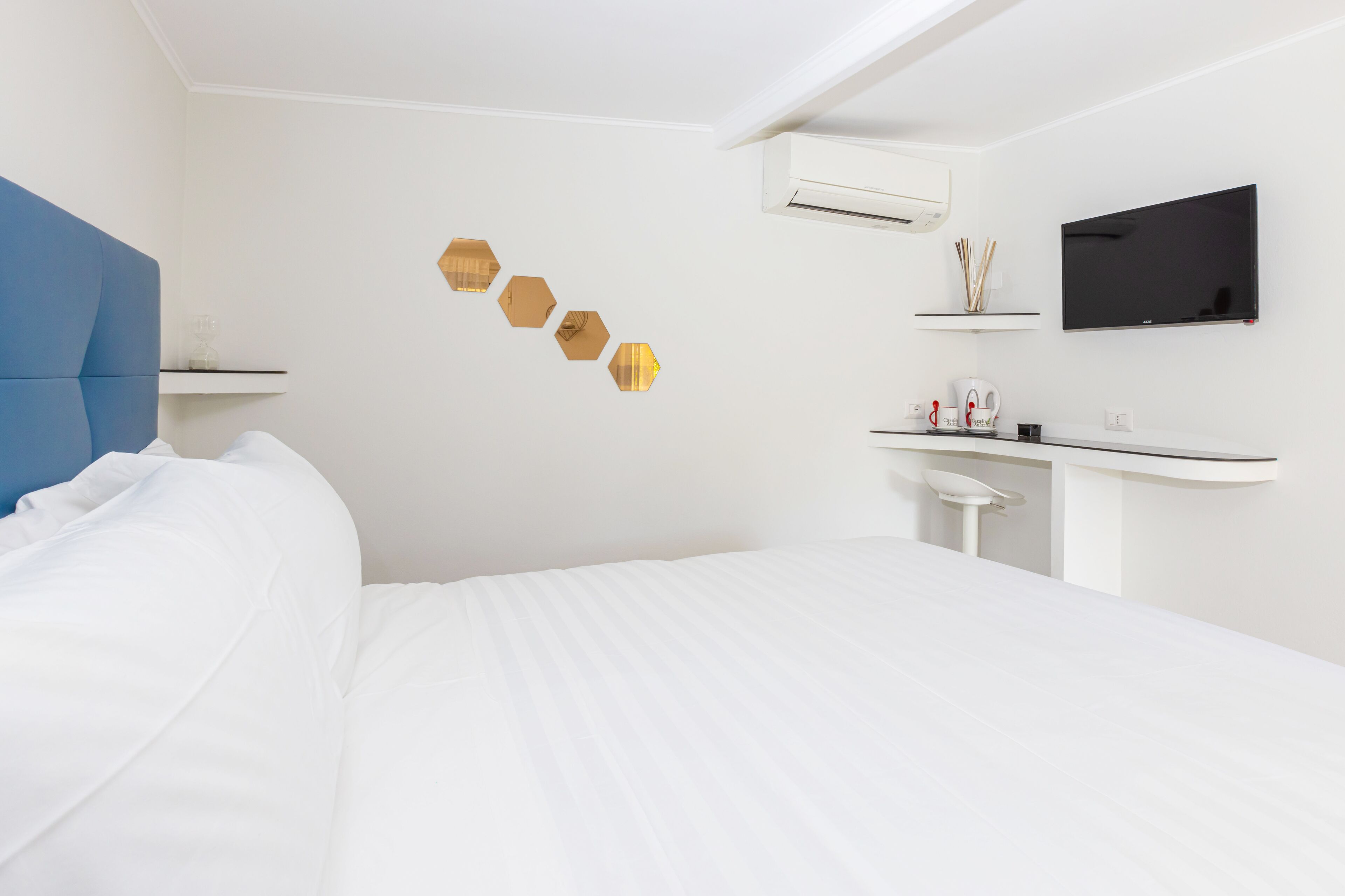 A modern hotel room with a bed, a flat-screen TV, a desk, and decorative wall art.