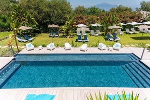 Una piscina al aire libre de temporada, sombrillas, tumbonas