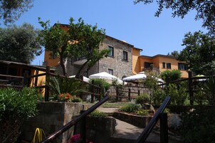 A courtyard with stone steps, a wooden fence, and outdoor seating with umbrellas.