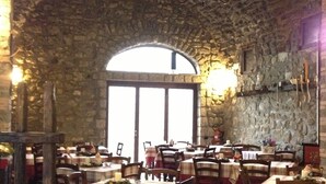 A restaurant with stone walls and arched windows, tables set with red and white tablecloths, and wooden chairs. - Relais Casale Antonietta (Sorrento)