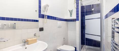 A bathroom with two sinks, a toilet, and a glass-enclosed shower.