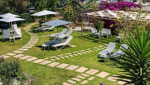 A garden with sun loungers, a pool, and a building with a red roof. - Relais Casale Antonietta (Sorrento)