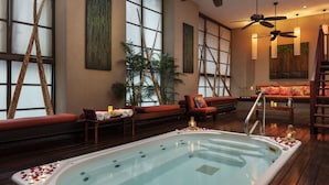 Un espace bien-être comprenant un jacuzzi, un plancher en bois, un canapé et un ventilateur de plafond.