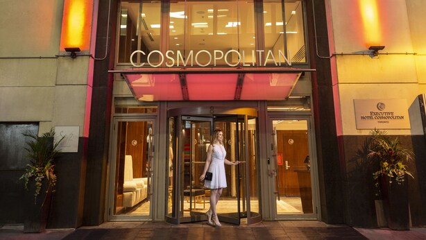 L’entrée d’un hôtel, avec une façade en verre et une enseigne portant l’inscription « COSMOPOLITAN ».