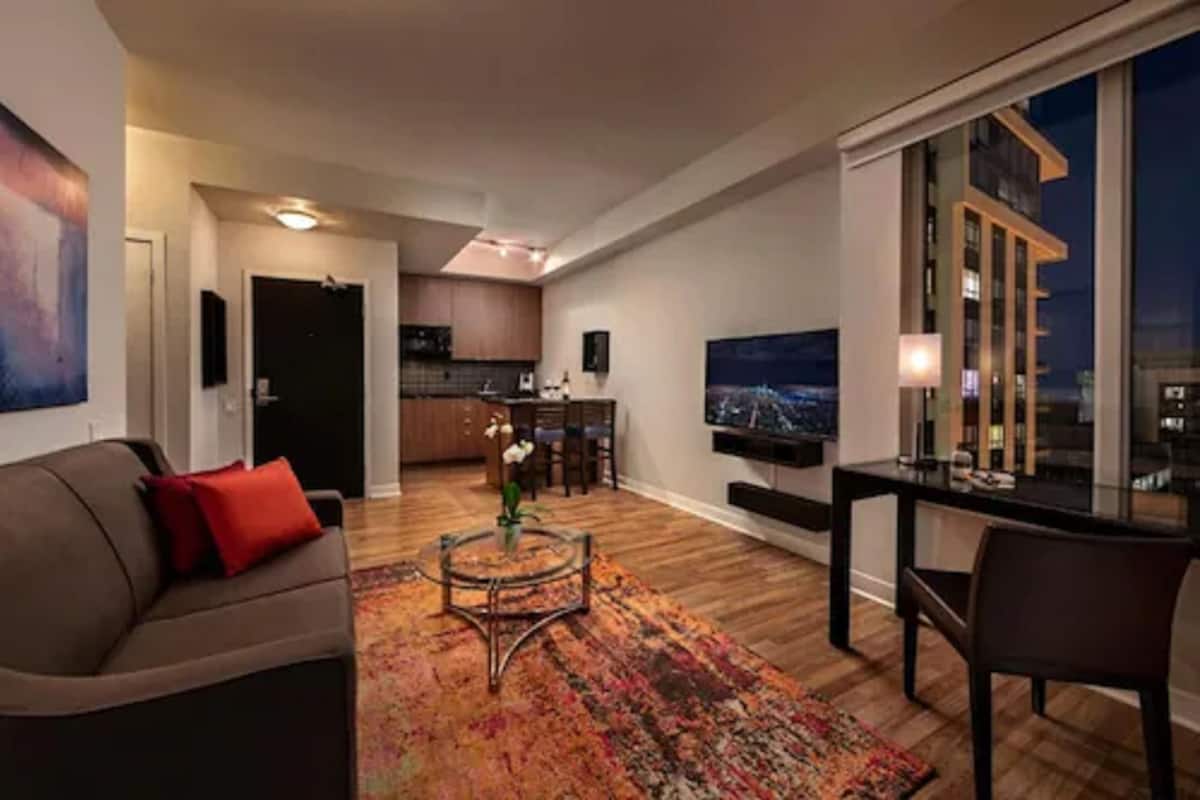 Ein modernes Wohnzimmer mit Sofa, Couchtisch und Blick auf die beleuchtete Stadt bei Nacht.