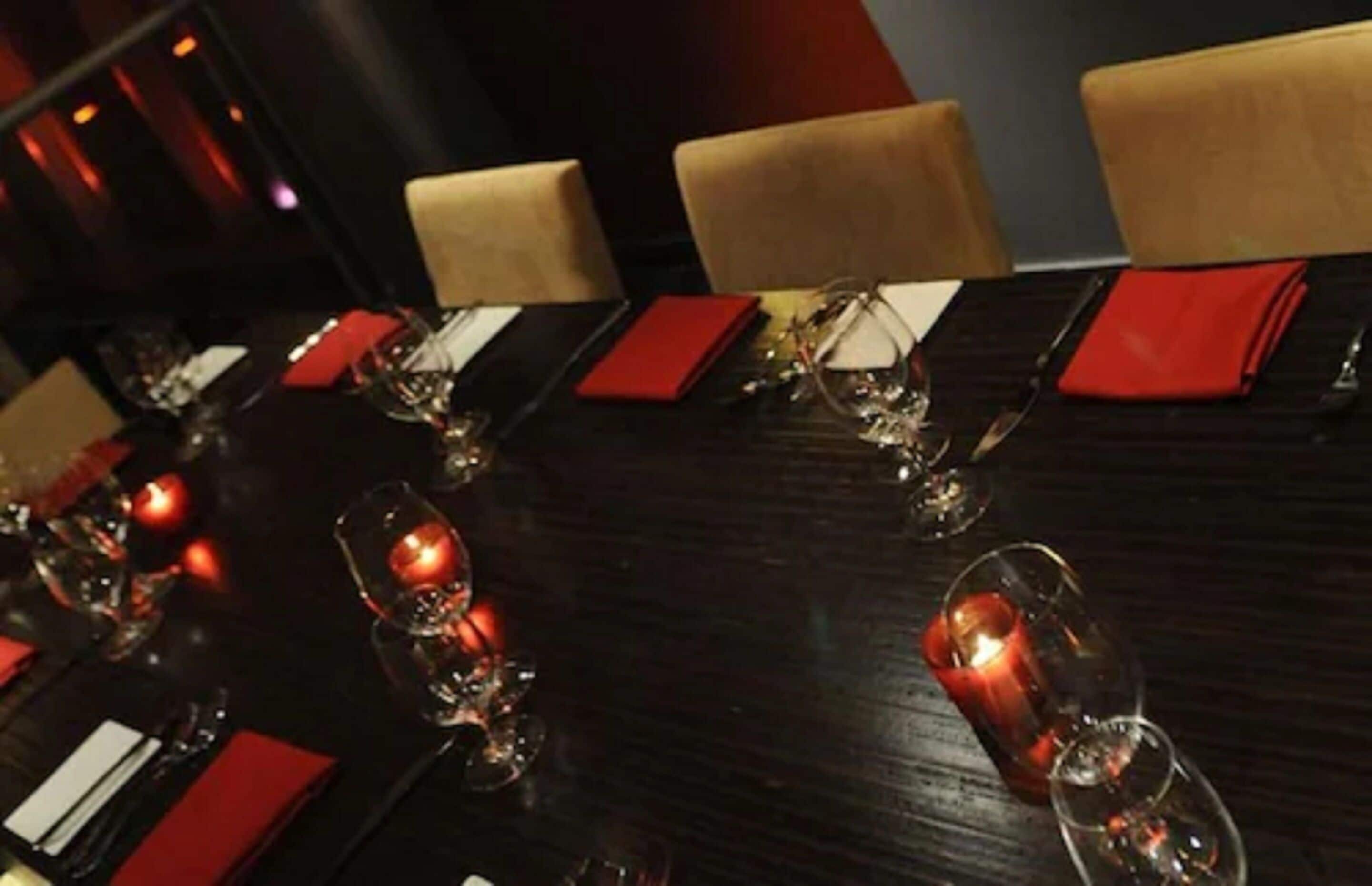 A dining table set with red napkins, wine glasses, and candles, indicating a formal dining setting.