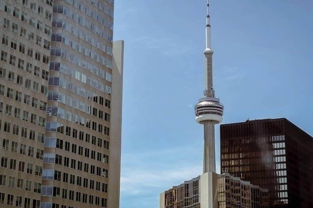 Ein Hochhaus mit markantem Turm, vermutlich ein Wahrzeichen, und angrenzende moderne Gebäude.