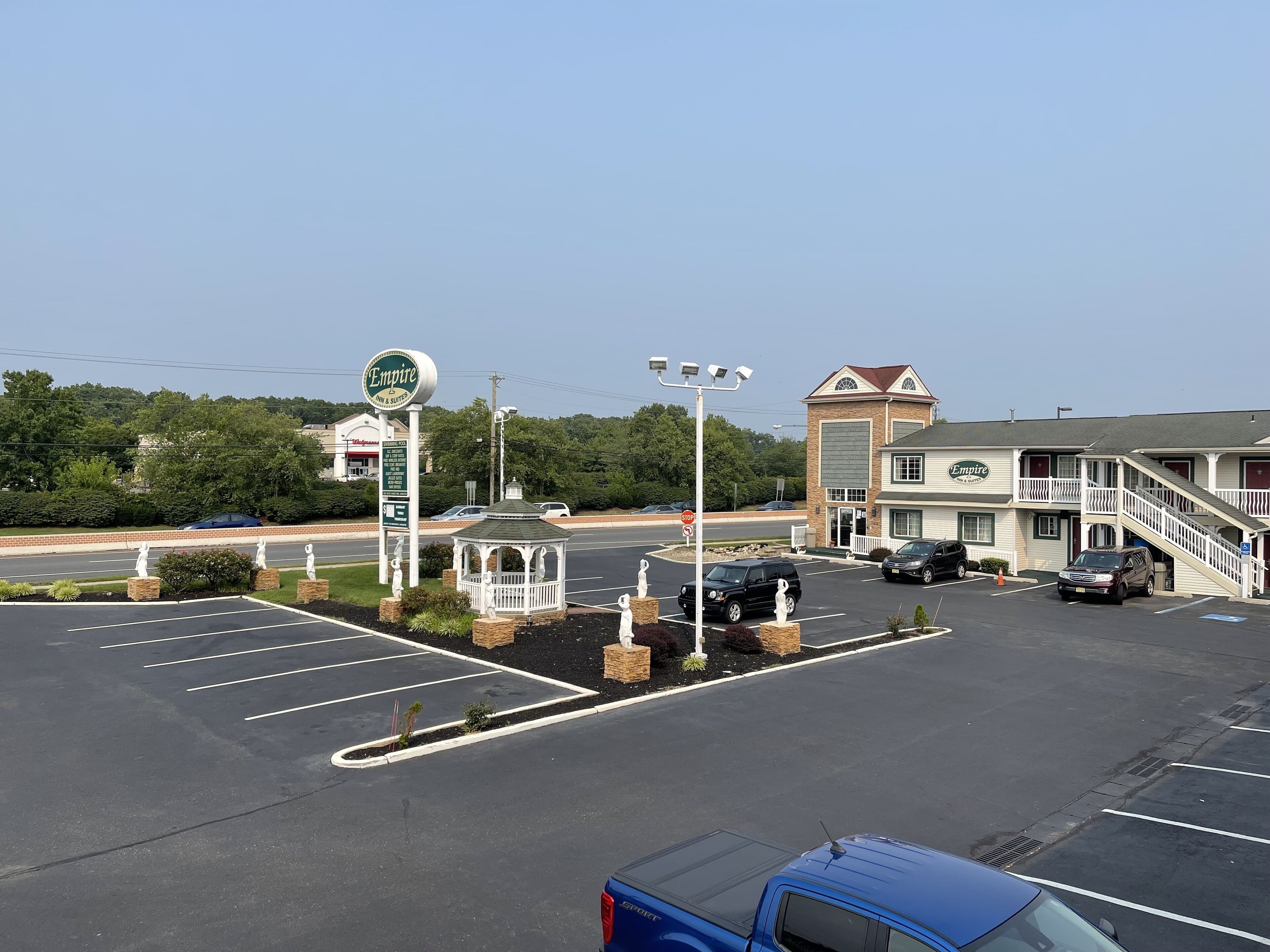 A parking lot with a gazebo, a sign for 'Empire Inn & Suites', and a building with a balcony.