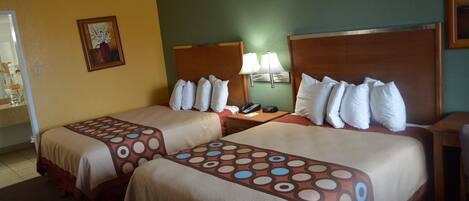 A hotel room with two beds, a nightstand with a lamp, and a painting on the wall.
