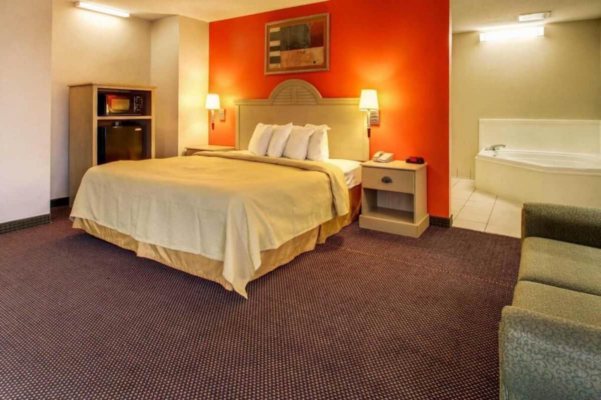 Een hotelkamer met een bed, nachtkastje, lamp en een kleine koelkast.
