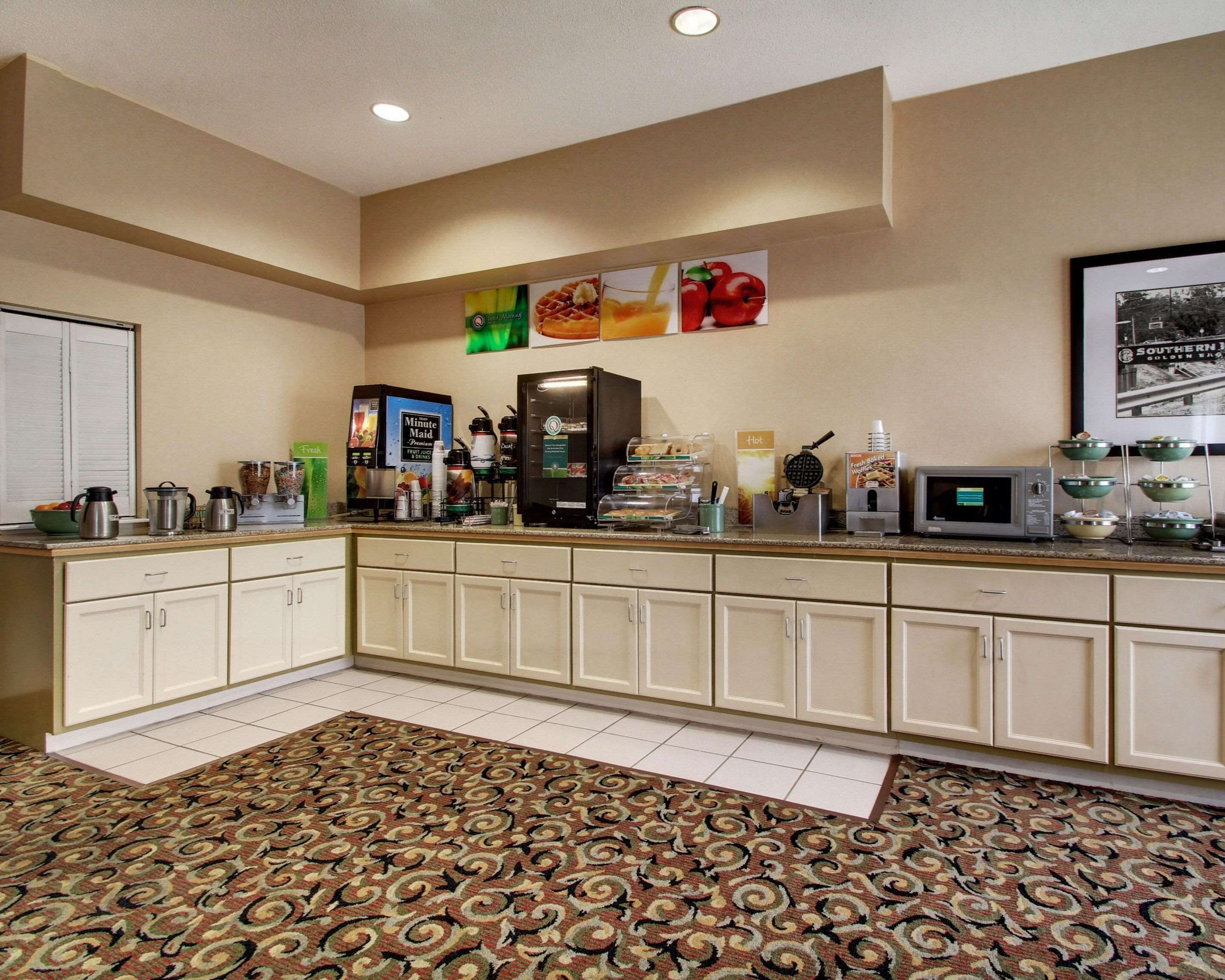 A hotel kitchen with a coffee machine, microwave, and various food items on the counter.