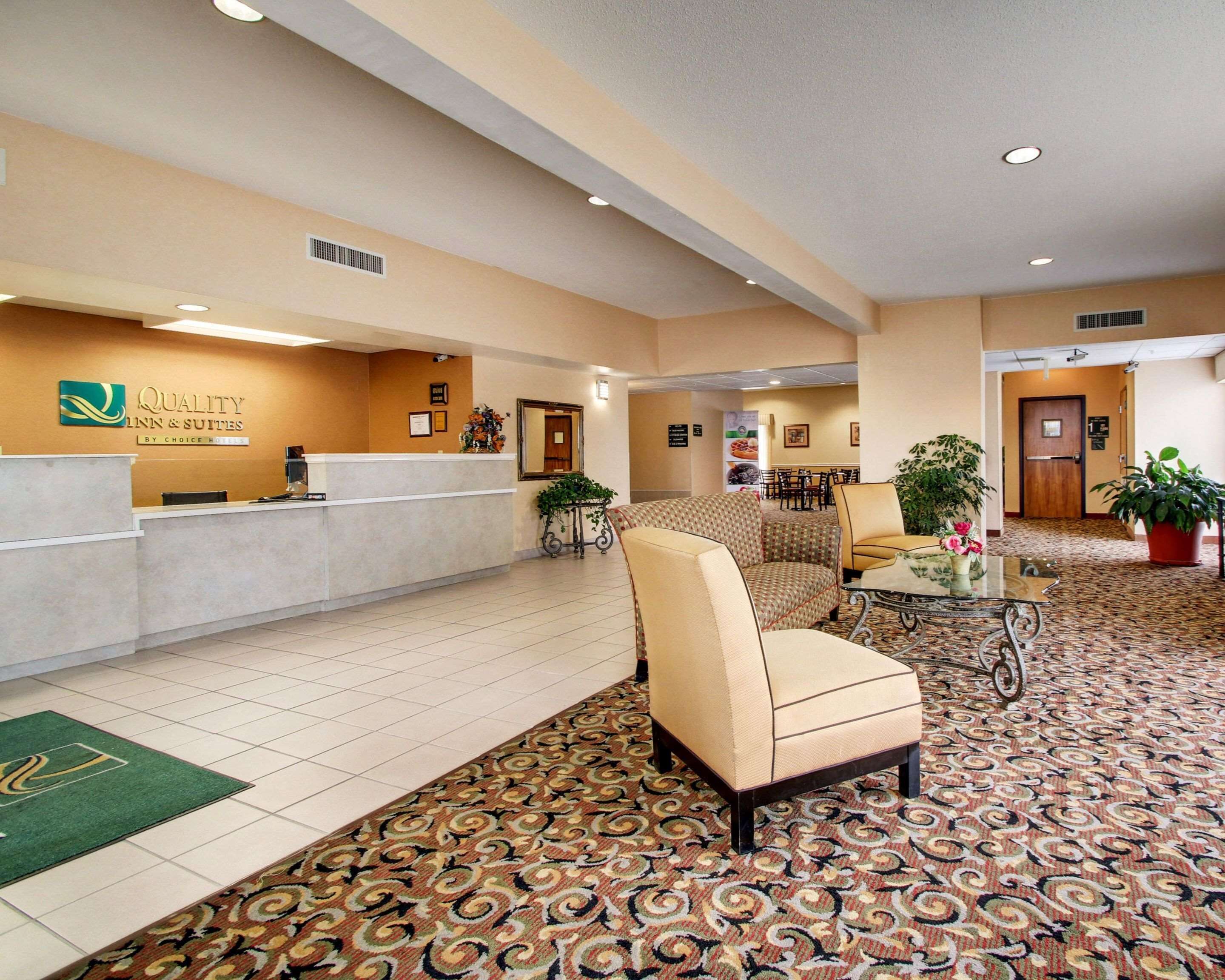 A hotel lobby with a reception desk, seating area, and a patterned carpet.