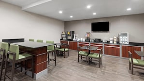 A modern hotel lobby with a long reception desk, several seating areas, and a flat-screen TV mounted on the wall. - Super 8 by Wyndham San Antonio/Alamodome Area (San Antonio)