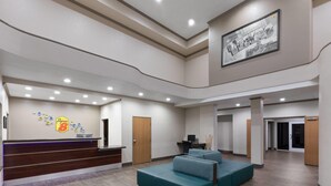 A spacious lobby with a reception desk, a teal sofa, and a framed picture on the wall. - Super 8 by Wyndham San Antonio/Alamodome Area (San Antonio)