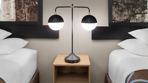 A hotel room with two beds, a nightstand with a lamp, and artwork on the walls. - Super 8 by Wyndham San Antonio/Alamodome Area (San Antonio)