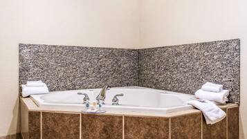 A corner bathroom with a freestanding bathtub, two faucets, and a towel rack.