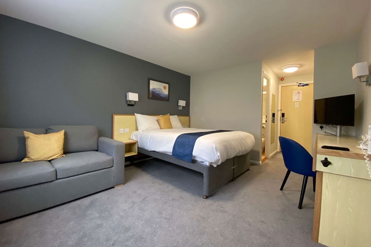 Een hotelkamer met een bed, een slaapbank, een bureau en een televisie.