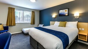 Hotelkamer met een groot bed, een bureau, een stoel, een raam met gordijnen en wandlampen.