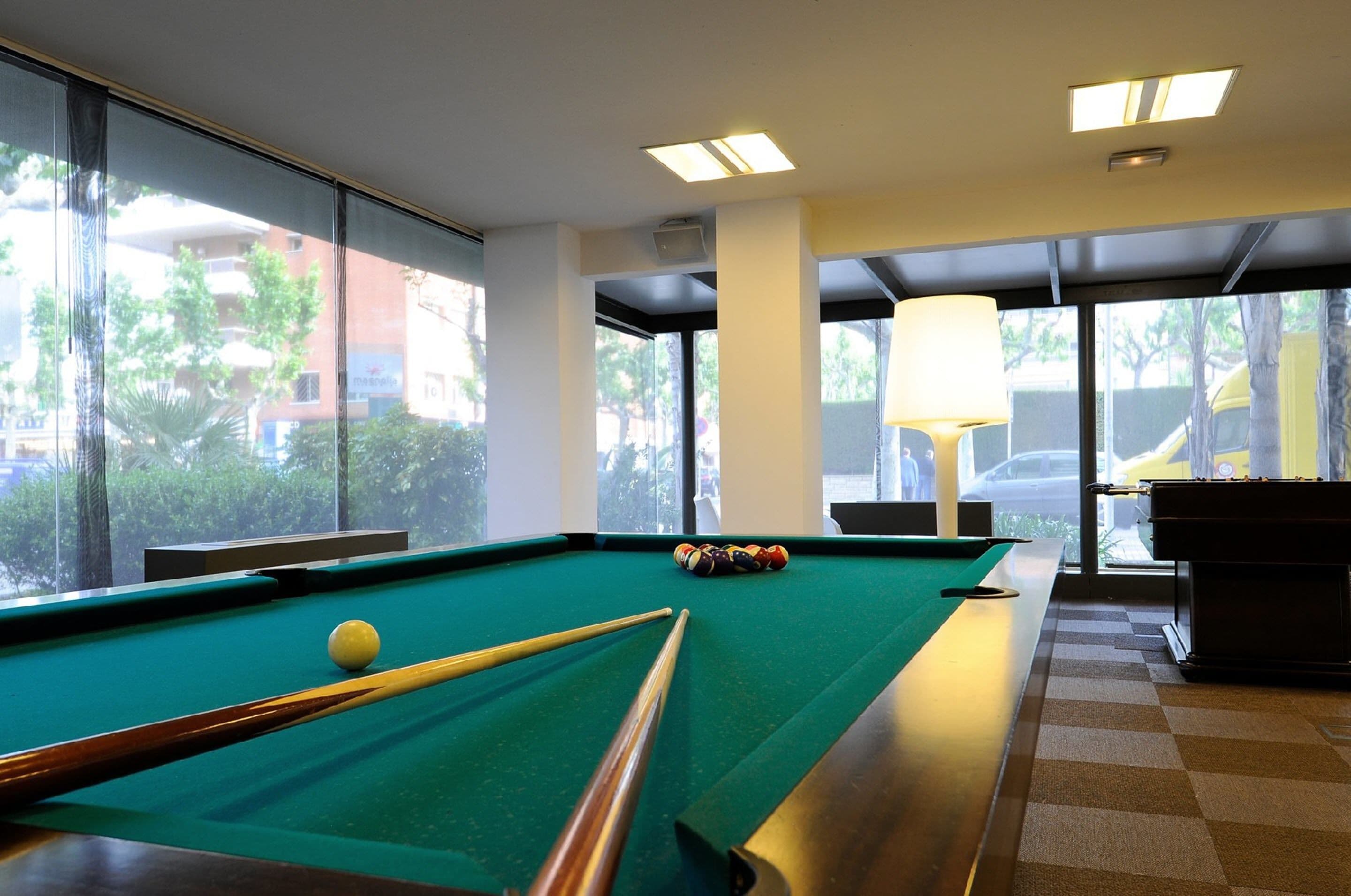 Una mesa de billar con bolas, una lámpara y vistas al exterior.