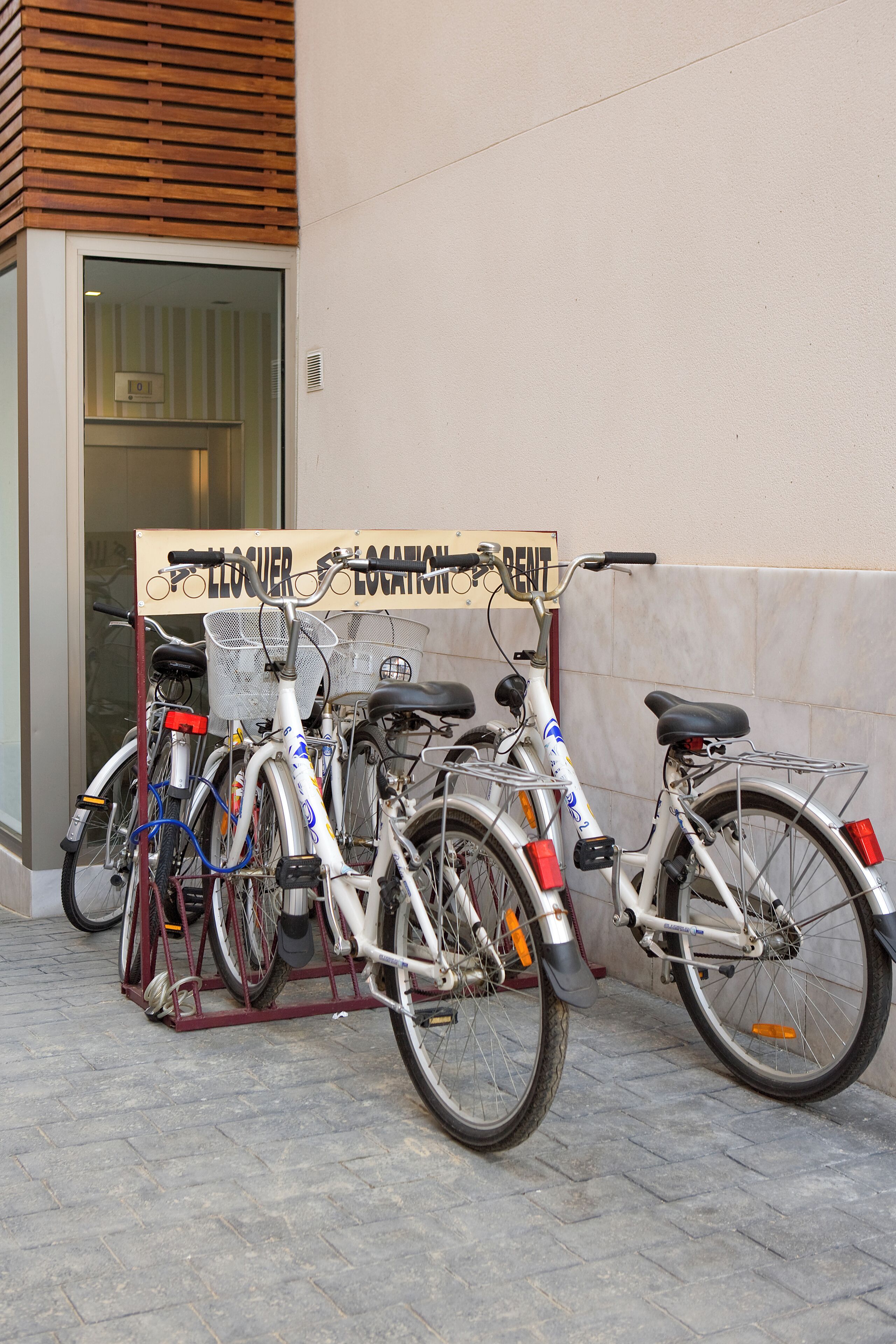 Fahrräder vor einem Gebäude, an dem ein Schild mit der Aufschrift 'LOCALEUR LOCATION RENT' angebracht ist.