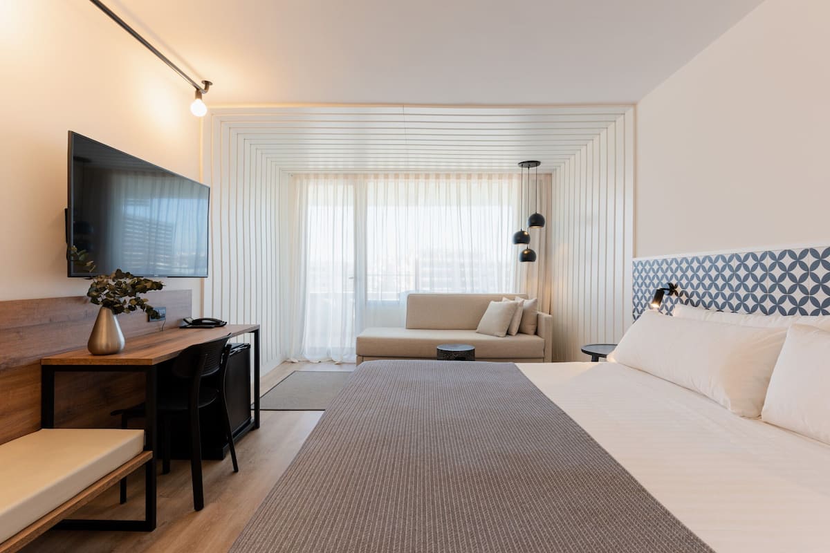 Een moderne hotelkamer met een bed, een bureau, een bank en een televisie.