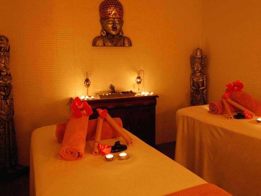 A spa room with two beds, candles, and statues.