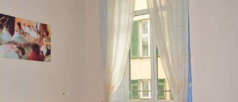 Un dormitorio con una cama grande, una cama más pequeña, una ventana con cortinas y un techo con frescos.