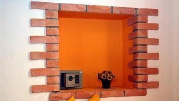 Un coin avec un mur en briques et une petite étagère.