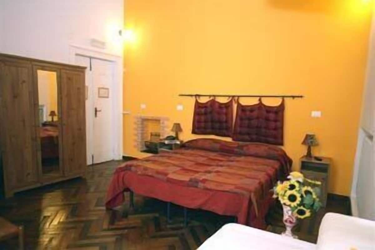 Un dormitorio con cama, mesita de noche, espejo y puerta.