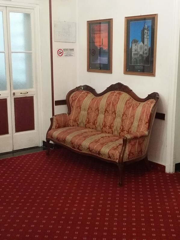 A room with a patterned sofa, a red carpet, and two framed pictures on the wall. - Balbi Hotel (Genoa)