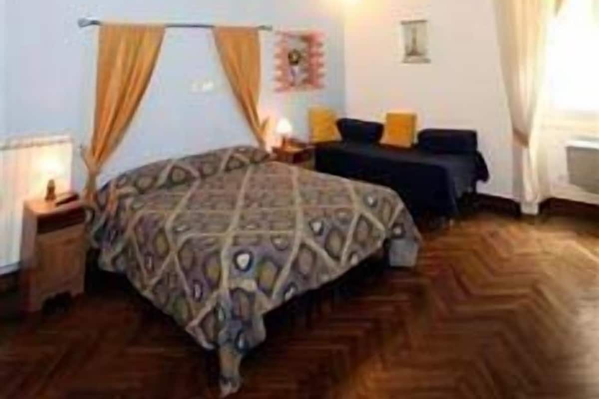 Un dormitorio con una cama grande, un techo con detalles intrincados y una ventana con cortinas.