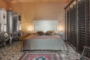 Una stanza con un letto, due mini-frigoriferi per vino a parete, un tappeto decorato e un pavimento piastrellato.