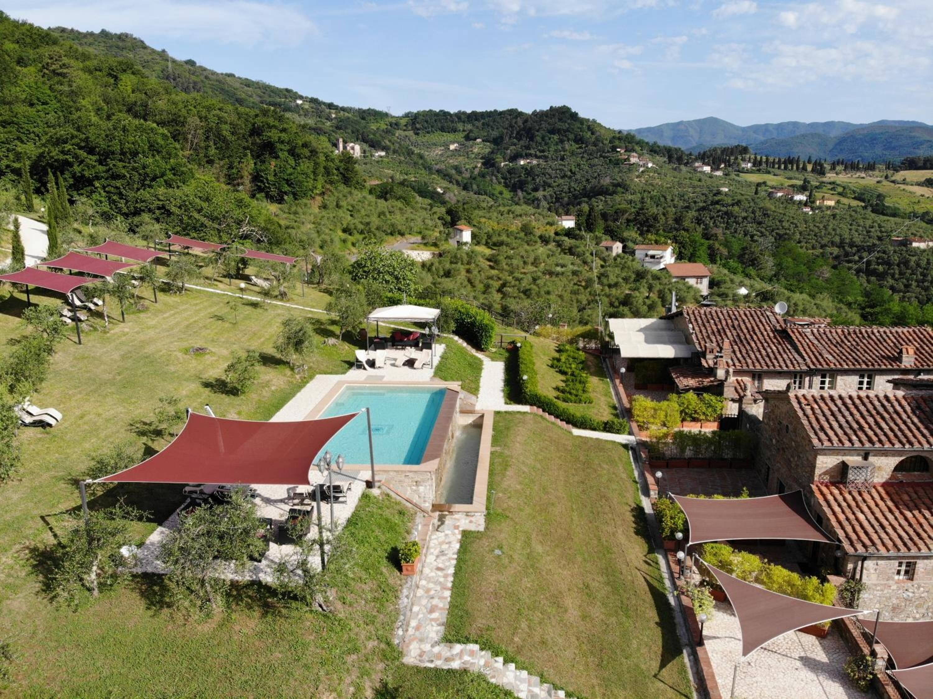 A hillside property with a swimming pool, outdoor seating, and a view of the surrounding hills.