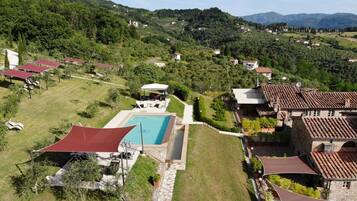 A hillside property with a swimming pool, outdoor seating, and a view of the surrounding hills.