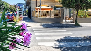 A hotel named 'HOTEL VITTORIA' with a signboard, a balcony, and a street view with a crosswalk and parked cars. - Hotel Vittoria (Viareggio)