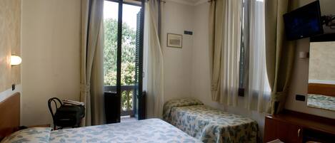 Habitación de hotel con dos camas, un escritorio, una silla, un televisor y una ventana con cortinas.