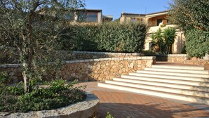 A stone retaining wall with steps leading up to a building.