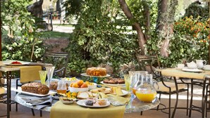 An outdoor dining area with tables, chairs, and a variety of food and drink items.