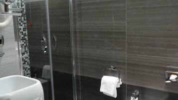 Un baño moderno con ducha de vidrio, un bidé y un lavamanos.