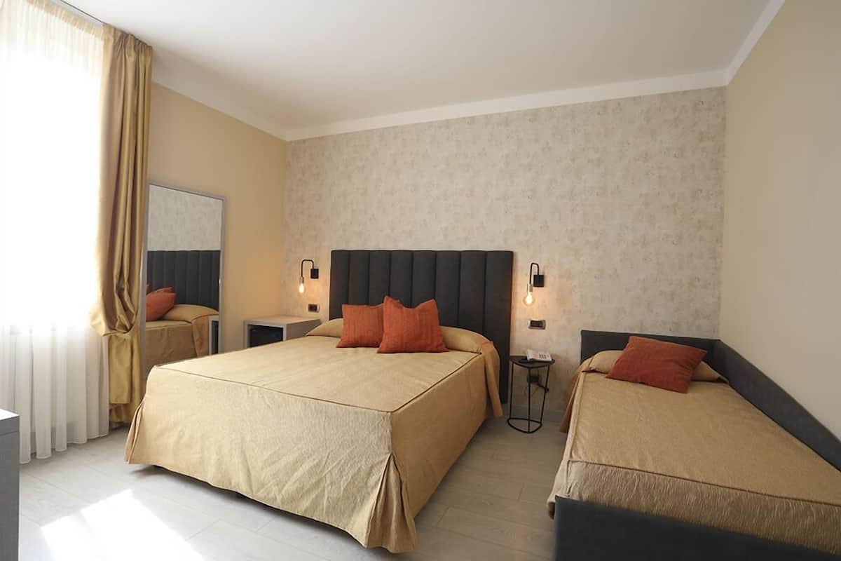 Ein Hotelzimmer mit zwei Betten, einem großen Spiegel und Wandleuchten.