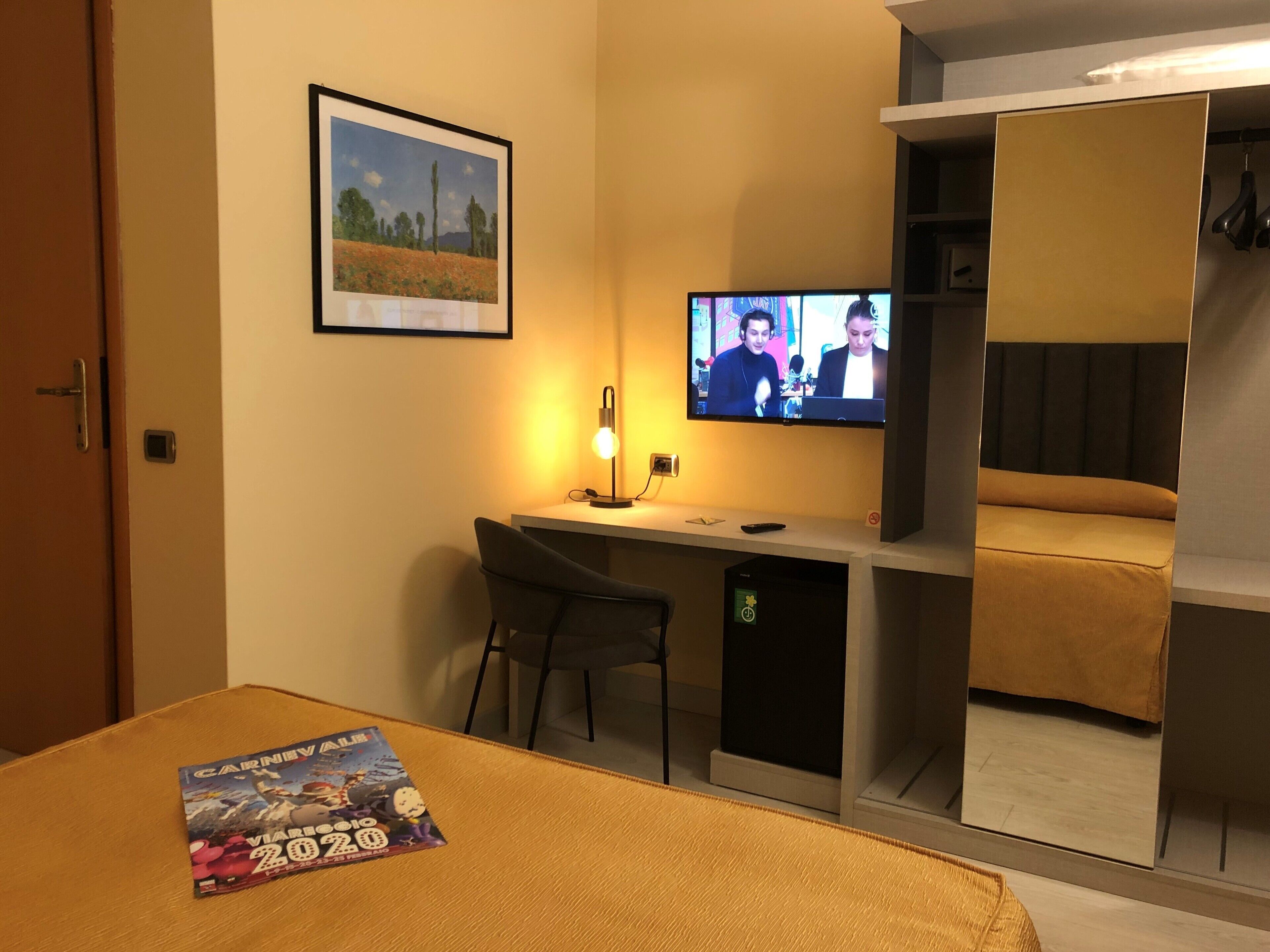 Une chambre d’hôtel comprenant un lit, un bureau avec une chaise, une télévision et une armoire.